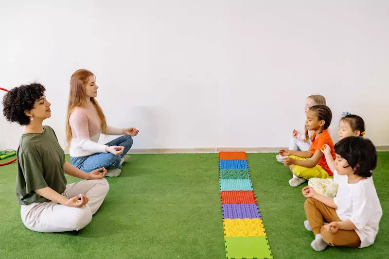 Two ladies meditating together with kids