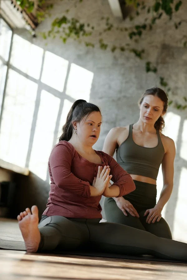 A lady instructor helping a participant with her pose.